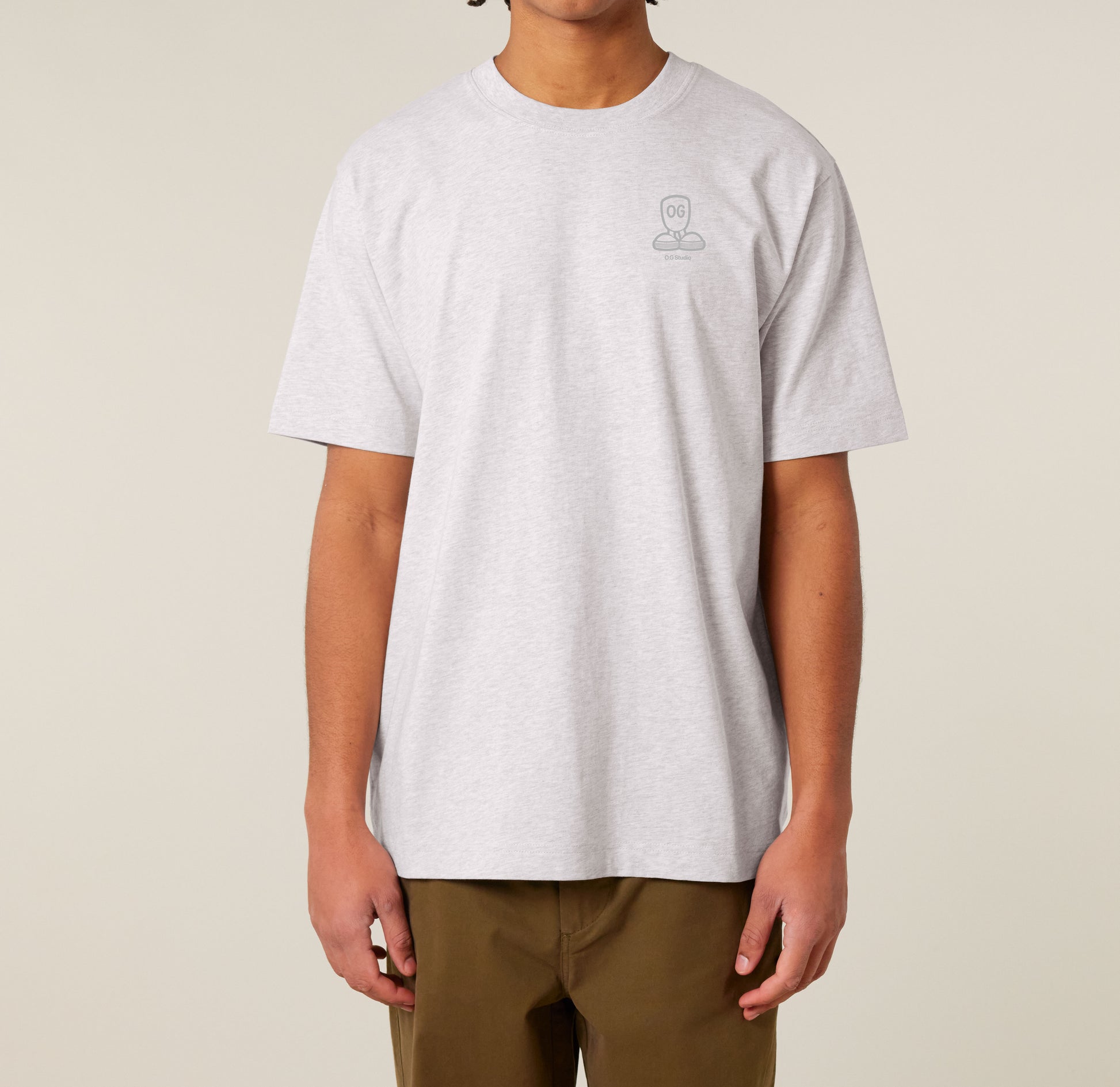 Lysegrå T-shirt med diskret OG.45™ logo på venstre bryst, båret af mand stående mod neutral baggrund.
