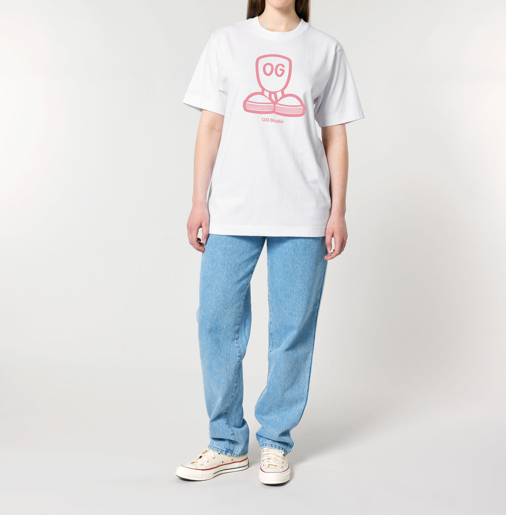 Person iført hvid OG.45™ T-shirt med lyserødt grafisk logo placeret centralt på brystet. Modellen står oprejst med armene afslappet langs siden, iført lyseblå jeans og hvide sneakers. Billedet er taget mod en neutral, lys baggrund og fremhæver T-shirtens pasform og tryk. Den minimalistiske stil og klare farver skaber et moderne streetwear-look, ideelt til både hverdag og casual outfits med kant og karakter.
